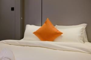 a bed with white pillows and an orange pillow at Metrolux By ZG in Ho Chi Minh City +121 photos