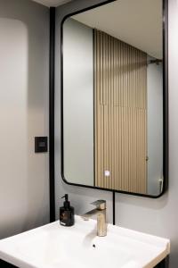 a bathroom with a mirror and a white sink at Metrolux By ZG in Ho Chi Minh City