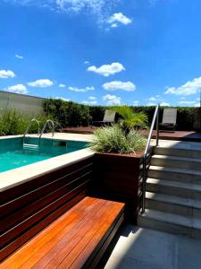 a swimming pool with a wooden bench and stairs next to a swimming pool at Apartamento Premium - Melhor vista de Curitiba in Curitiba