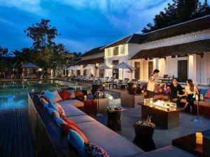 a hotel patio with couches and a pool at night at Sofitel Luang Prabang in Luang Prabang
