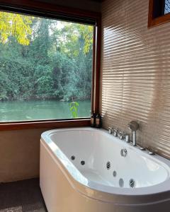 a bath tub in a bathroom with a large window at River tales ริเวอร์เทลส์แก่งกระจาน in Phetchaburi +36 photos