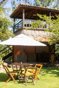 a table and chairs with an umbrella in front of a house at Casa Manoel Facão in Atins