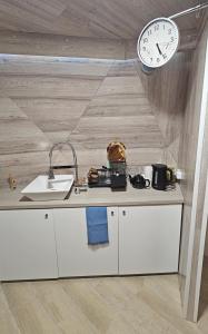 a kitchen with a sink and a clock on a wall at Trys su puse upės in Dzidai +20 photos