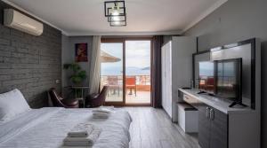 a bedroom with a bed and a television and a balcony at Stone House Foça Otel in Yenifoça