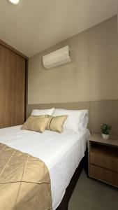 a bedroom with a large white bed with a air conditioner at Studio moderno, rooftop com piscina, próx UFU in Uberlândia +28 photos
