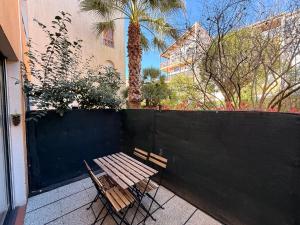 a wooden bench sitting next to a fence with a palm tree at Le Cosy du Lagon bleu in Fréjus