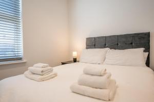 a bedroom with a white bed with towels on it at 38 Prospect Place, Leiston in Leiston