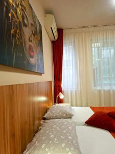 a bedroom with a bed and a painting on the wall at Private Rooms Valis in Varna City