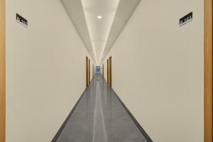 a long corridor with a white wall and a long hallway at Hotel O Ciapus Bogor in Bogor
