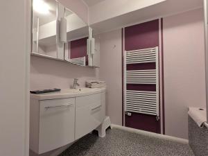 a white bathroom with a sink and a mirror at Suite Hotel Villa Erika in Borkum +124 photos