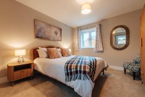 a bedroom with a bed and a mirror and a chair at The Stables in Huntingdon
