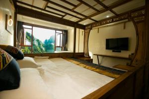 a large white bed in a room with a window at Mountain-scenery inn in Zhangjiajie