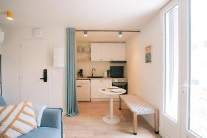 a living room with a table and a kitchen at Les archives de Georges 153 - Appart' de standing en centre-ville - Balcon privé, Climatisation, Caméra de vidéo surveillance in Périgueux