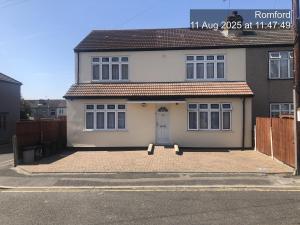 a white house with a door on a street at Montrose Guest House in Romford