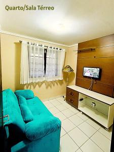 a living room with a blue couch and a tv at Chalé Esmeralda in Gravatá