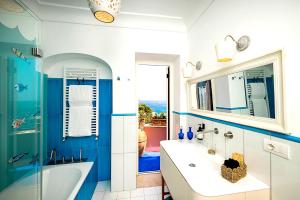 a blue and white bathroom with a tub and a sink at Luxury Maison Cherie - Positano Charme & Sea View in Positano +85 photos