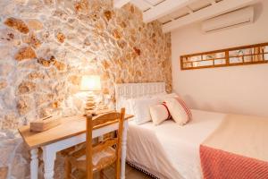 a bedroom with a bed and a table and a desk at Calma Hotel in Ciutadella