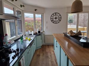 a kitchen with blue cabinets and a clock on the wall at La Maison Elegance & Charme in Marquise