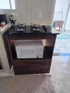 a kitchen counter with a stove and a microwave at Microcasa espaçosa e acolhedora in Caraguatatuba +7 photos