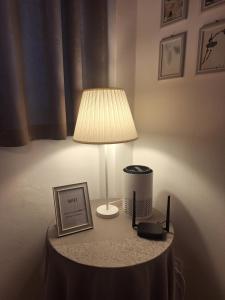 a lamp on a table with a picture and a phone at Gioberti in Casale Monferrato