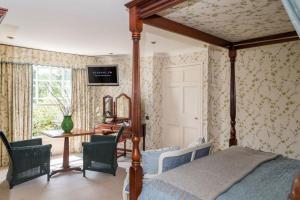 a bedroom with a bed and a table with chairs at The Eastbury & Spa in Sherborne
