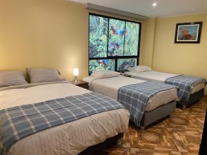 three beds in a room with a window at Posada Miraflores in Lima