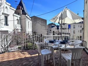 a white table and chairs on a balcony with an umbrella at Intermezzo - 1 chambre - Terrasse in Châtel-Guyon