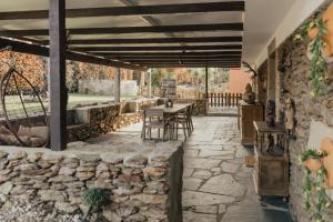 a stone patio with tables and chairs and a stone wall at Refúgio da Cancela - Arouca Stay in Arouca