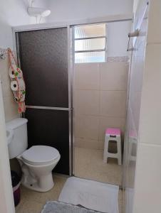 a bathroom with a toilet and a glass shower door at Microcasa espaçosa e acolhedora in Caraguatatuba