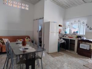 a kitchen with a table and a white refrigerator at Microcasa espaçosa e acolhedora in Caraguatatuba