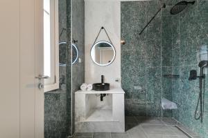 a bathroom with a shower with a sink and a mirror at Tepeleni, Parga Apts with Pool in Agiá