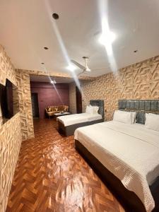 a hotel room with two beds and a couch at Royal Confort Inn in Karachi