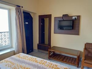 a bedroom with a bed and a tv on the wall at Scindhia Guest House in Varanasi