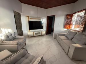 a living room with couches and a flat screen tv at Casarão Figueiredo in Presidente Figueiredo