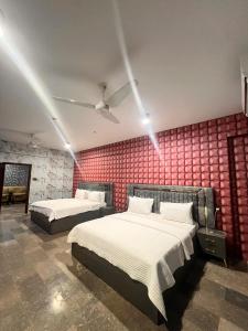 a bedroom with two beds and a red wall at Royal Confort Inn in Karachi +4 photos
