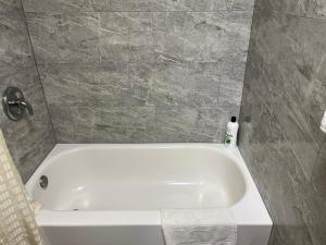 a white bath tub in a bathroom with a tile wall at Bragg Motel in Upper Marlboro