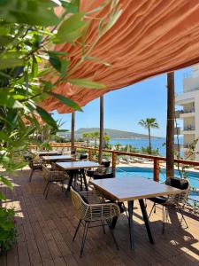 a row of tables and chairs on a deck with a pool at Harbour Hotel in Sarandë