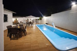 a swimming pool with a table and chairs and a table and a dining room at Casarão Figueiredo in Presidente Figueiredo