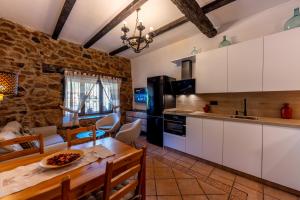 a kitchen with white cabinets and a dining table at El Cerrillo in Navaconcejo