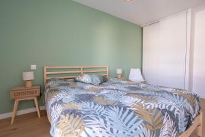 a bedroom with a bed with a blue and white comforter at L'Escale d'Erdeven - En centre-bourg in Erdeven