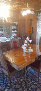 ein Holztisch mit Blumen und eine Gitarre in einem Zimmer in der Unterkunft Mashal in Srinagar