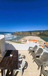 a patio with a table and chairs and a beach at Sol da Praia in Odeceixe