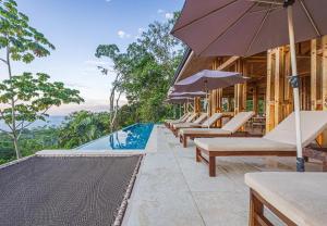 an outdoor pool with lounge chairs and an umbrella at Tiki Villas Rainforest Lodge - Adults Only in Uvita