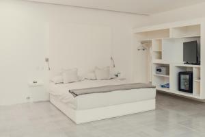 a white bedroom with a white bed and a tv at Hotel Azul de Oaxaca in Oaxaca City