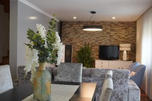 a living room with a table with a vase of flowers at Casa das Caldas in Caldelas
