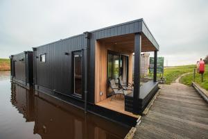 a black tiny house on a body of water at Tiny boat house #2 in Garnwerd