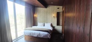 a bedroom with a bed and a large window at Pine Breeze Luxe in Gulmarg