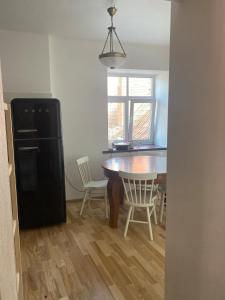 a kitchen with a table and chairs and a black refrigerator at St Johns sunny side apartment in Cēsis