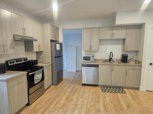 a large kitchen with wooden cabinets and stainless steel appliances at Modern Private Suite Fast WiFi Parking Quiet Stay in Prince George