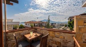 a patio with a table and chairs on a stone wall at Stone House Foça Otel in Yenifoça